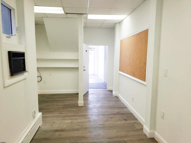 corridor featuring wood finished floors, a paneled ceiling, and baseboards
