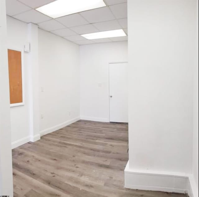 spare room with wood finished floors, baseboards, and a paneled ceiling