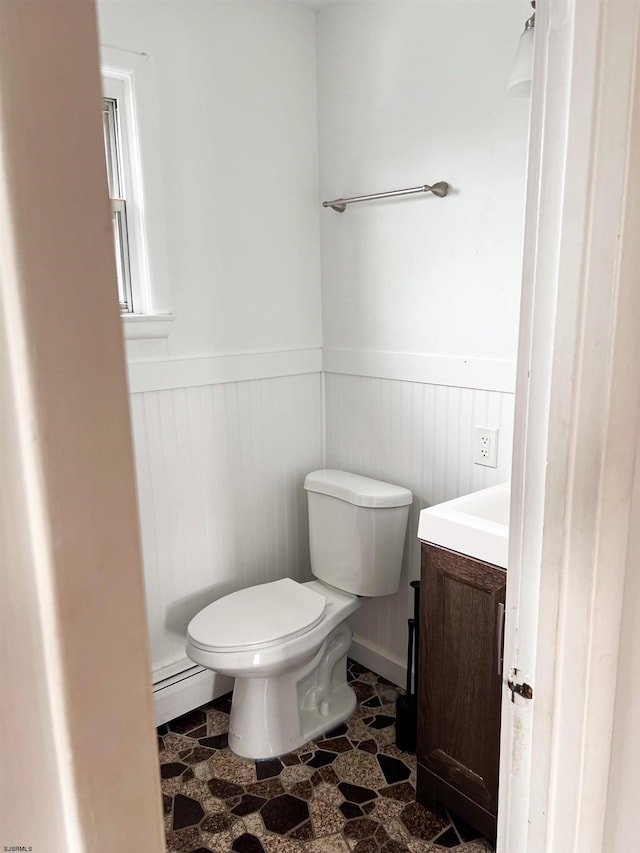 bathroom with wainscoting, toilet, a baseboard heating unit, vanity, and tile patterned floors