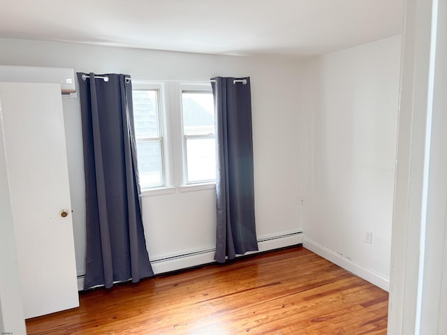 spare room featuring light wood-style floors and a baseboard heating unit