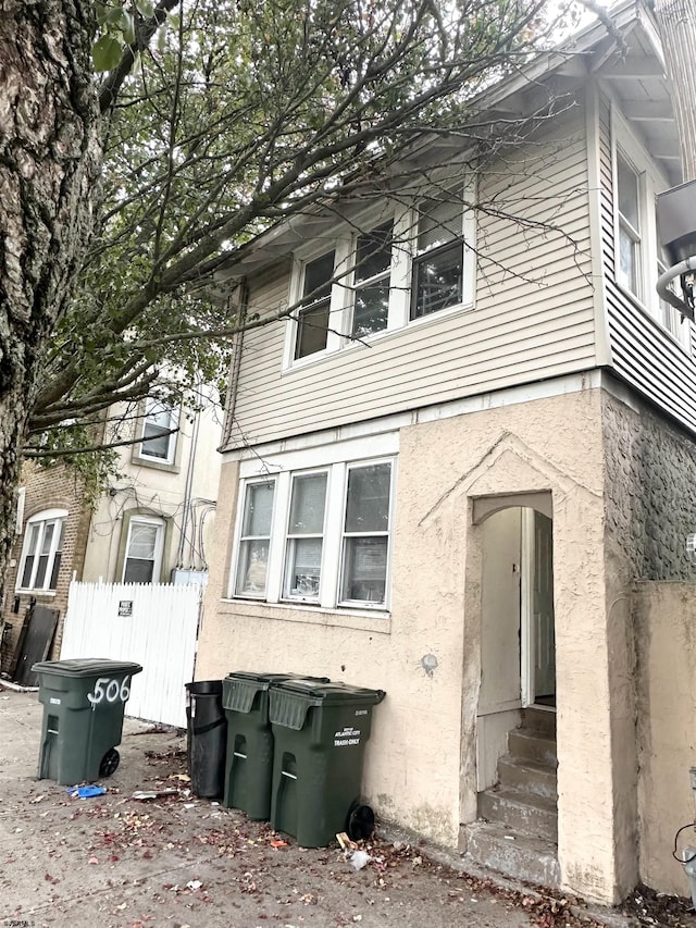 view of front of house with fence, entry steps, and stucco siding