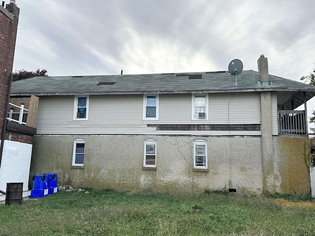 rear view of property featuring stucco siding, a balcony, and a lawn