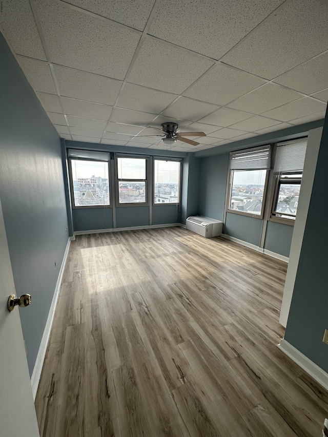 unfurnished room featuring baseboards, a ceiling fan, a paneled ceiling, and wood finished floors
