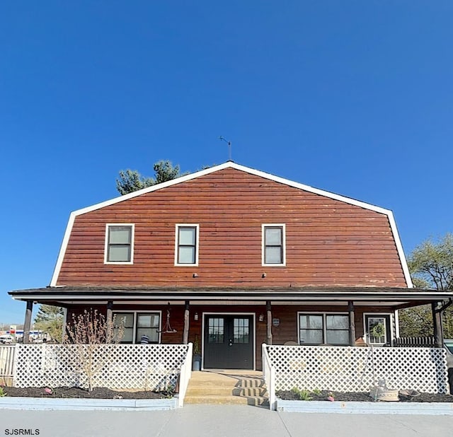 view of front of property with a porch and a gambrel roof
