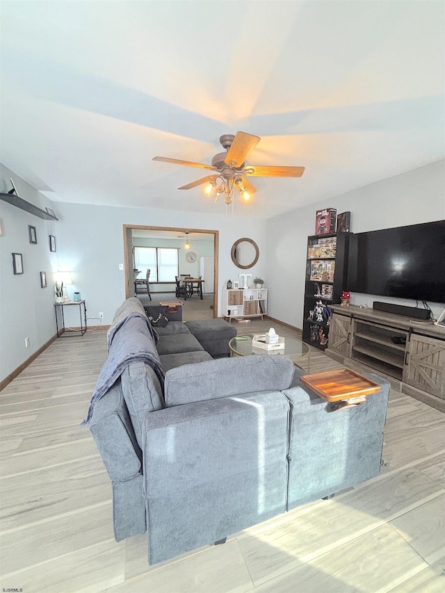 living area with a ceiling fan, wood finished floors, and baseboards