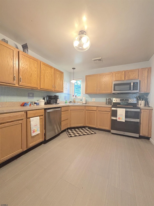 kitchen featuring stainless steel appliances, a sink, light countertops, and tasteful backsplash