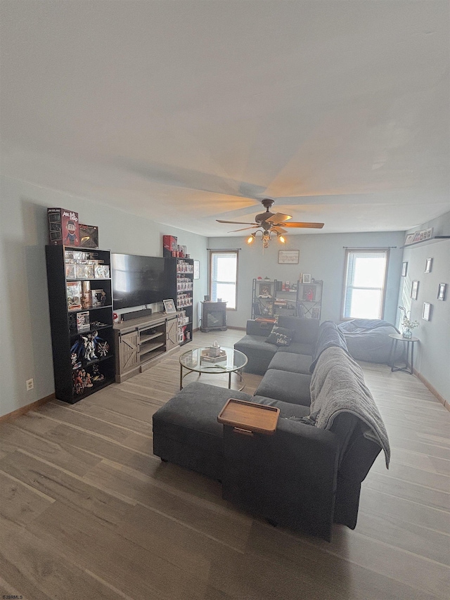 living area featuring plenty of natural light, ceiling fan, wood finished floors, and baseboards