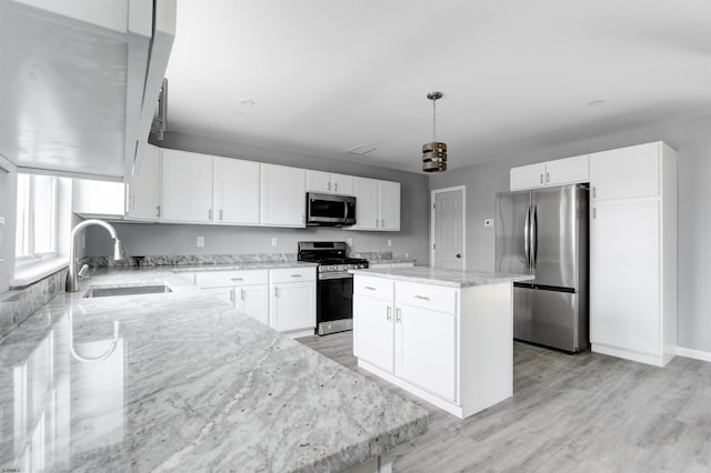 kitchen with appliances with stainless steel finishes, a sink, light stone counters, light wood-style flooring, and white cabinets