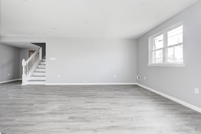 unfurnished room with stairway, baseboards, and wood finished floors