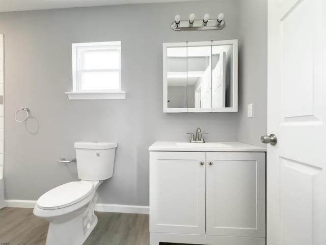 bathroom with baseboards, wood finished floors, toilet, and vanity