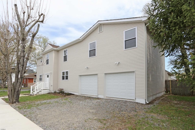 view of side of property with a garage, driveway, and fence