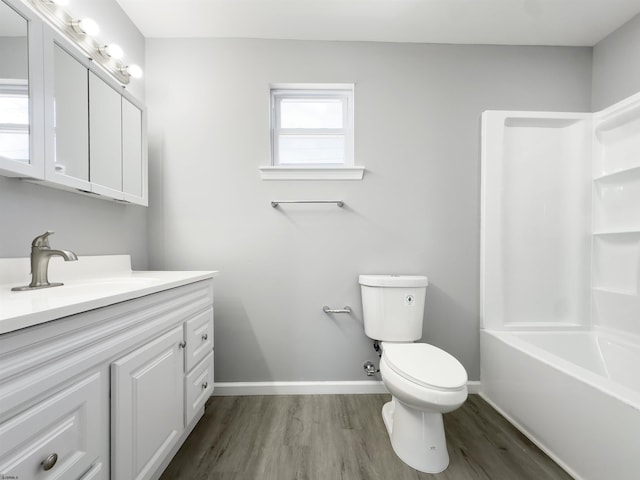 bathroom featuring wood finished floors, toilet, vanity, and baseboards