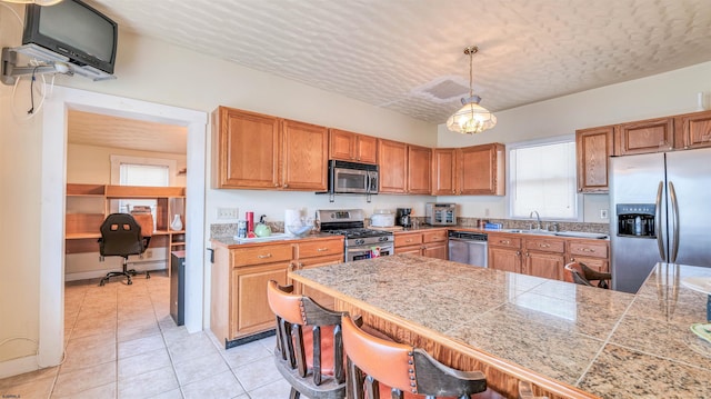 919 Broad St, Pleasantville, NJ 08232 - kitchen featuring appliances with stainless steel finishes, tile counters, a sink, a breakfast bar area, and brown cabinets