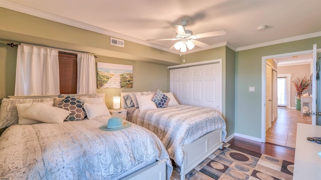 bedroom with ornamental molding, a closet, wood finished floors, baseboards, and ceiling fan
