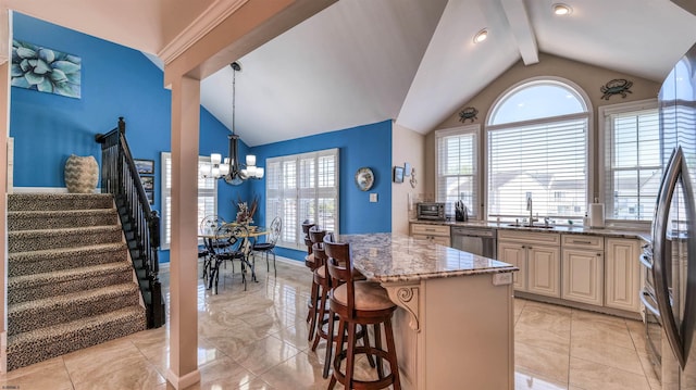 kitchen with lofted ceiling, appliances with stainless steel finishes, light stone countertops, a chandelier, and a center island