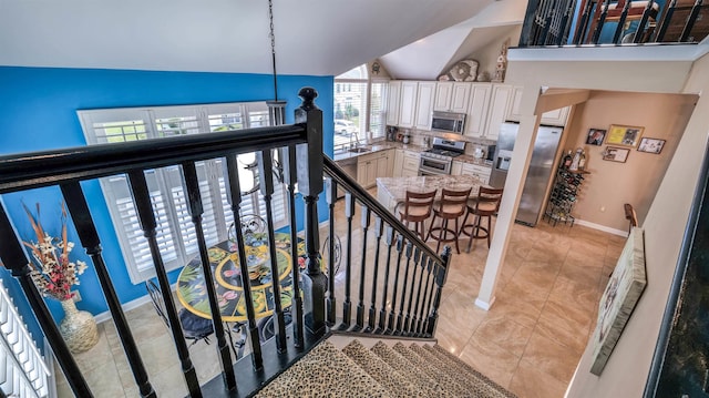staircase featuring baseboards, high vaulted ceiling, and tile patterned flooring