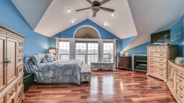 bedroom with lofted ceiling, a fireplace, wood finished floors, and ceiling fan