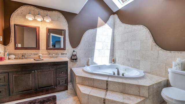 bathroom featuring tile walls, a skylight, toilet, a tub with jets, and double vanity