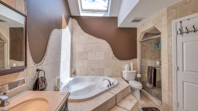 bathroom featuring tile walls, a shower stall, a skylight, a jetted tub, and vanity