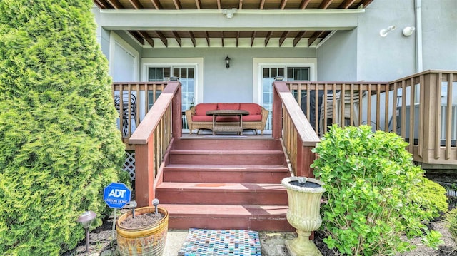 view of exterior entry with stucco siding and a deck