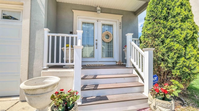 property entrance featuring a porch, stucco siding, and french doors