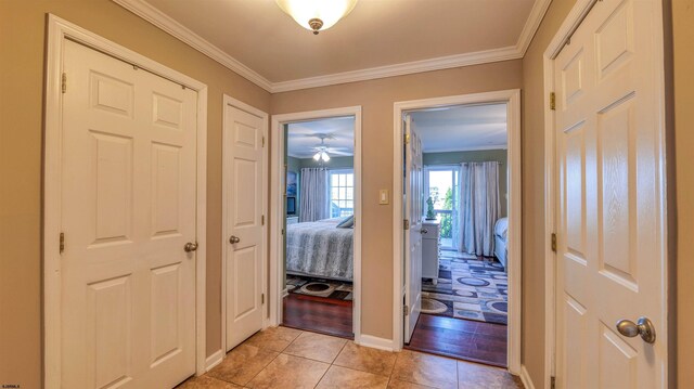 hall featuring light tile patterned flooring, ornamental molding, and baseboards