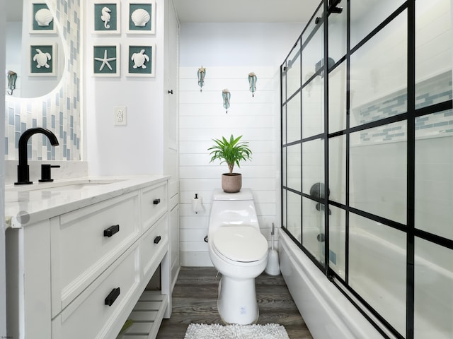 bathroom featuring wood finished floors, toilet, vanity, and enclosed tub / shower combo