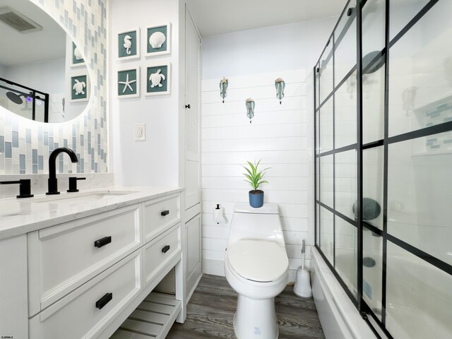 full bath with wood finished floors, enclosed tub / shower combo, vanity, toilet, and backsplash
