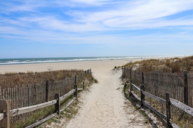 water view featuring nearby beach and fence