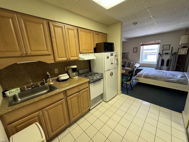 kitchen with electric range, a sink, under cabinet range hood, freestanding refrigerator, and a paneled ceiling