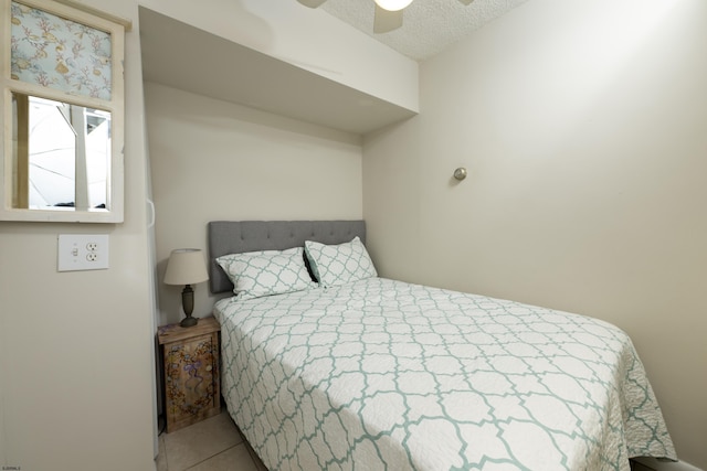 bedroom featuring ceiling fan, tile patterned floors, and a textured ceiling
