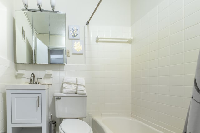 full bathroom featuring toilet, tile walls, washtub / shower combination, and vanity