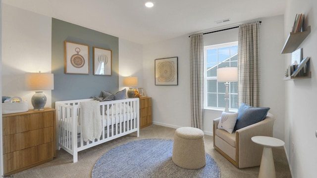 carpeted bedroom featuring a nursery area and baseboards