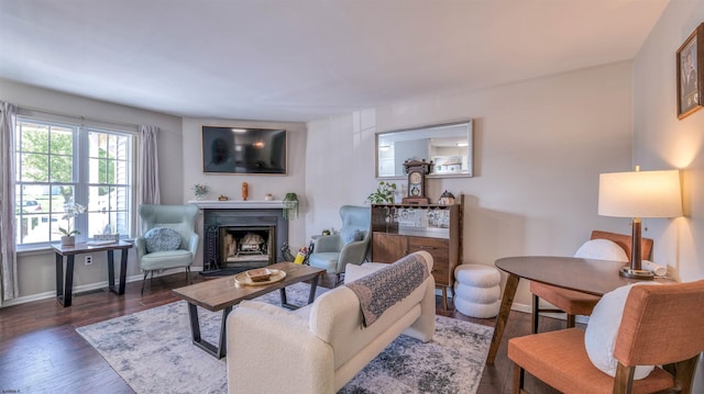 living room featuring baseboards, a fireplace with flush hearth, and wood finished floors