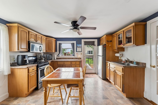 1224 Front St, Mauricetown, NJ 08329 - kitchen featuring stainless steel appliances, a sink, glass insert cabinets, brown cabinetry, and ceiling fan