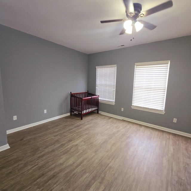 206 N S Carolina Ave, Atlantic City, NJ 08401 - unfurnished bedroom featuring dark wood-style floors, baseboards, a ceiling fan, and a crib