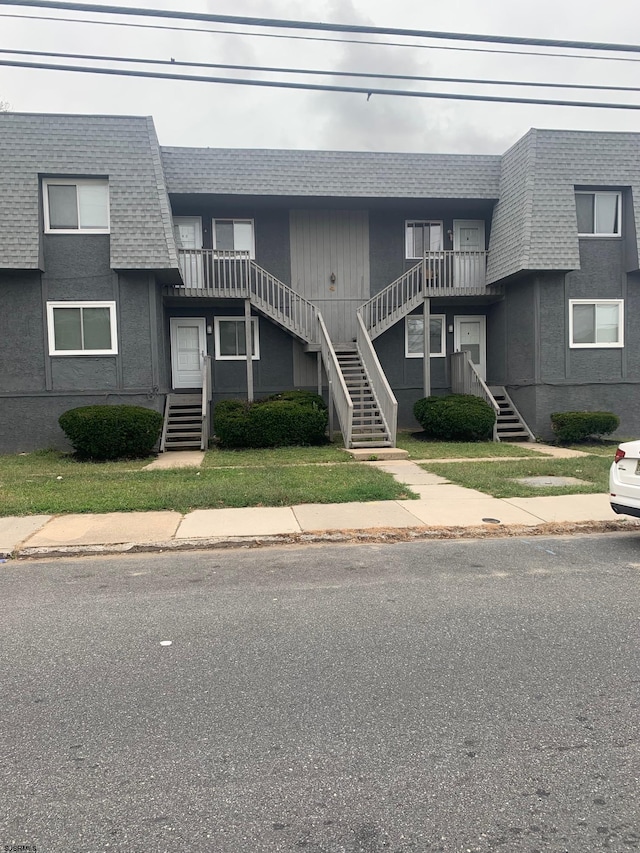 view of front of home featuring stairs, roof with shingles, and mansard roof