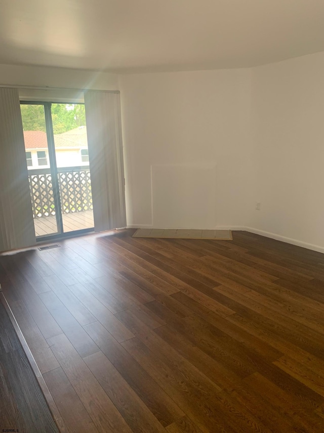 empty room with dark wood-style flooring and baseboards