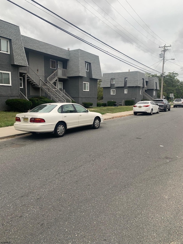 view of asphalt street featuring curbs, sidewalks, street lighting, and stairs