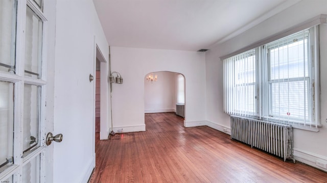 711 N Ohio Ave, Atlantic City, NJ 08401 - empty room with radiator, arched walkways, hardwood / wood-style flooring, a chandelier, and baseboards