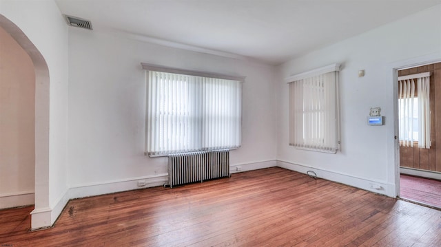 711 N Ohio Ave, Atlantic City, NJ 08401 - unfurnished room with radiator heating unit, plenty of natural light, arched walkways, and hardwood / wood-style flooring