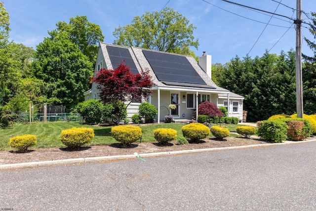 view of front of property featuring a chimney, solar panels, and a shingled roof