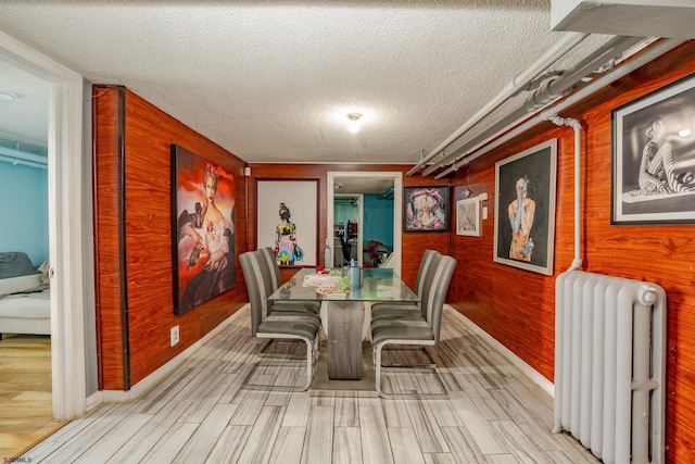 32 N Florida Ave, Atlantic City, NJ 08401 - dining space with radiator, wood walls, a textured ceiling, wood finish floors, and baseboards