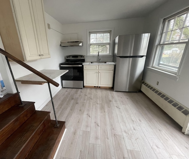 27 E Pierson Ave, Somers Point, NJ 08244 - kitchen featuring appliances with stainless steel finishes, under cabinet range hood, a sink, light wood-type flooring, and a baseboard heating unit