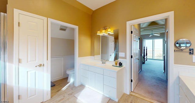 full bathroom featuring vanity, a wainscoted wall, wood finished floors, toilet, and ceiling fan