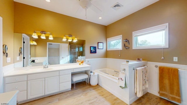 bathroom with a stall shower, vanity, a garden tub, wood finished floors, and a ceiling fan
