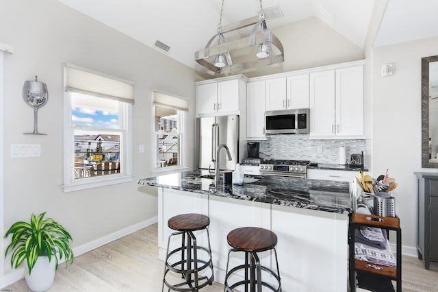 9315 Ventnor Ave, Margate, NJ 08402 - kitchen with stainless steel appliances, lofted ceiling, decorative backsplash, a kitchen bar, and light wood-style flooring