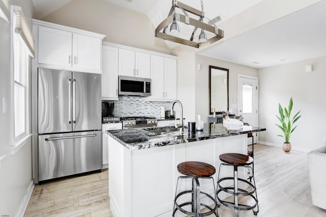 9315 Ventnor Ave, Margate, NJ 08402 - kitchen featuring appliances with stainless steel finishes, a sink, decorative backsplash, light wood-type flooring, and dark stone counters