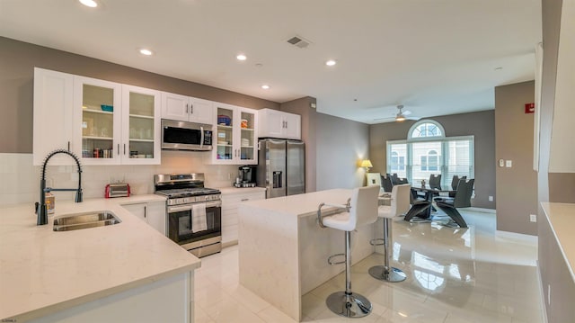 kitchen with appliances with stainless steel finishes, a sink, a kitchen breakfast bar, decorative backsplash, and an office area