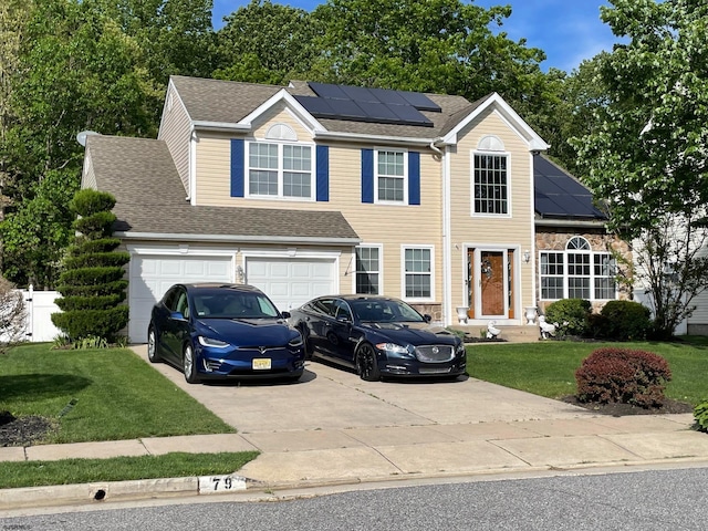 view of front of house with driveway, a front lawn, roof mounted solar panels, an attached garage, and a shingled roof